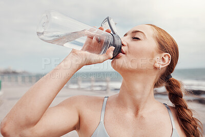 Buy stock photo Fitness, woman and drinking water at the beach after running, exercise or cardio workout in Cape Town. Female runner with bottle and natural drink for thirst, hydration or aqua liquid for sport break