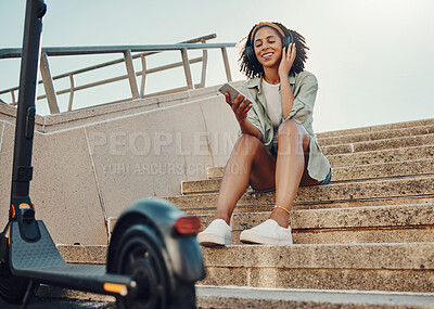 Buy stock photo Black woman outdoor, smartphone and headphones with scooter, music and travel with 5g network for audio streaming in city. Sustainable transportation, listen to audio or podcast and relax on steps 