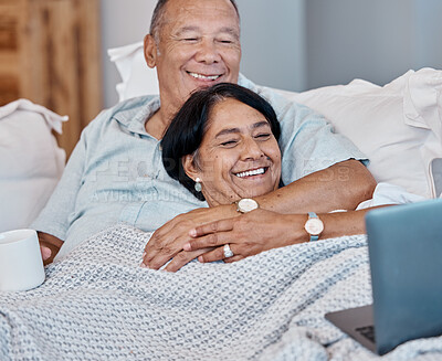 Buy stock photo Elderly couple streaming a movie on a laptop while relaxing on a sofa in their living room. Love, home and happy senior man and woman in retirement watching a video on computer together on a couch.
