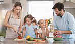 Parents, food and children cooking in kitchen with vegetables for nutrition, vegan lifestyle and healthy eating. Food, family and mom, dad and girls learning and help for meal prep, dinner or lunch