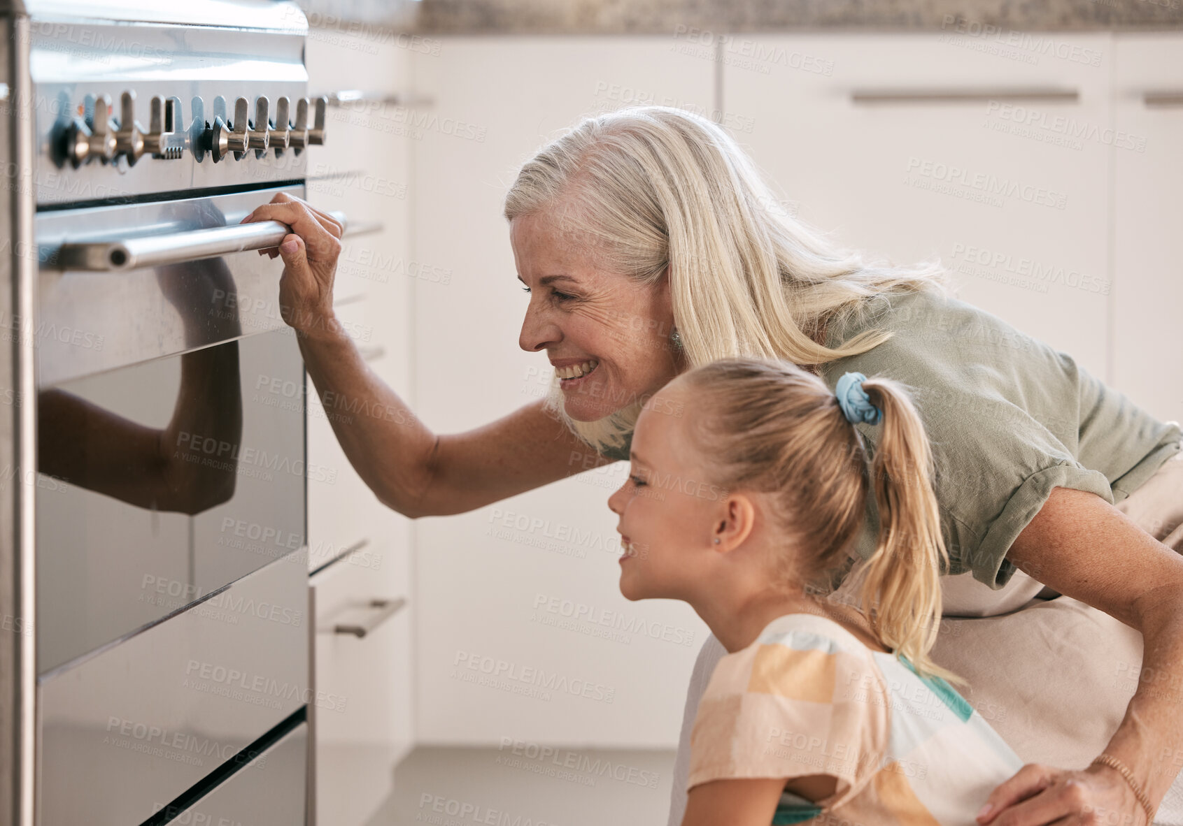 Buy stock photo Baking, kitchen and grandmother with a child by the oven watching the cake, cookies or pie bake. Happy, smile and senior woman with a girl kid cooking for dinner, party or event at their home.