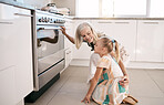 Kitchen, happy and grandmother with a kid by the oven watching the cake, cookies or pie bake. Happiness, smile and senior woman with a girl child cooking or baking for dinner, party or event at home.