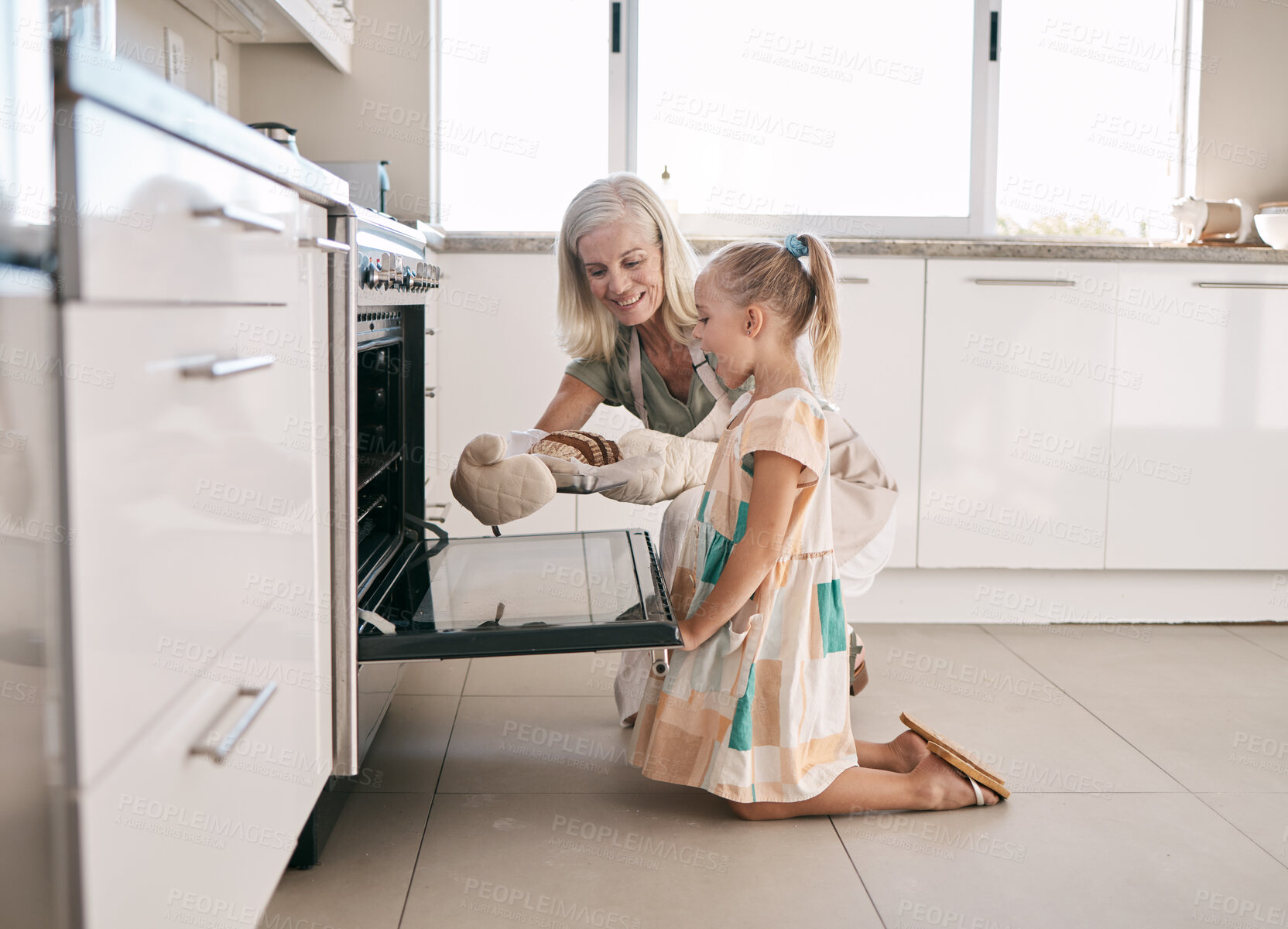 Buy stock photo Kitchen, grandmother and child baking bread together in oven in their modern family home. Happy, smile and girl kid helping senior woman grandma in retirement bake for dinner, party or event at house