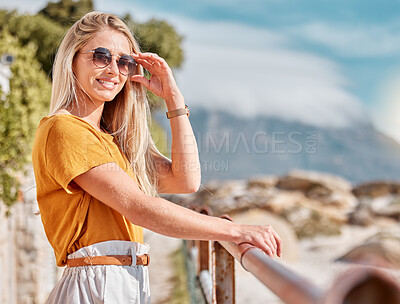 Buy stock photo Portrait, beach and fashion with a woman outdoor in nature by the ocean or sea in the summer season. Travel, freedom and happy smile with a young female standing outside on a coastal shoreline