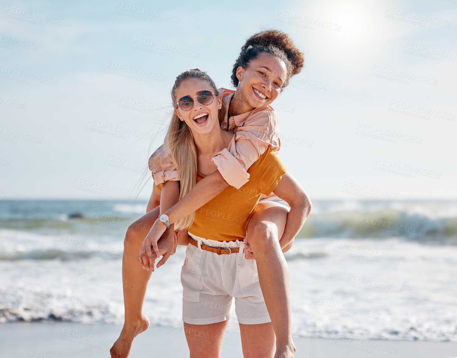 Buy stock photo Piggyback, beach and couple of friends in portrait for lgbtq, lesbian or gay love, freedom on summer vacation. Blue sky, ocean and diversity women on date, fun support and excited valentines holiday