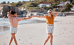 Couple holding hands on beach, lesbian and fun by ocean, gay women outdoor with adventure and freedom to love. Interracial, laugh and holiday in Australia, lgbtq with travel and happy dance together