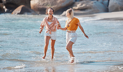 Buy stock photo Couple holding hands on beach, lesbian and happy in ocean, gay women outdoor with adventure and freedom to love. Interracial, laughter and holiday in Australia, lgbtq with travel and running in water
