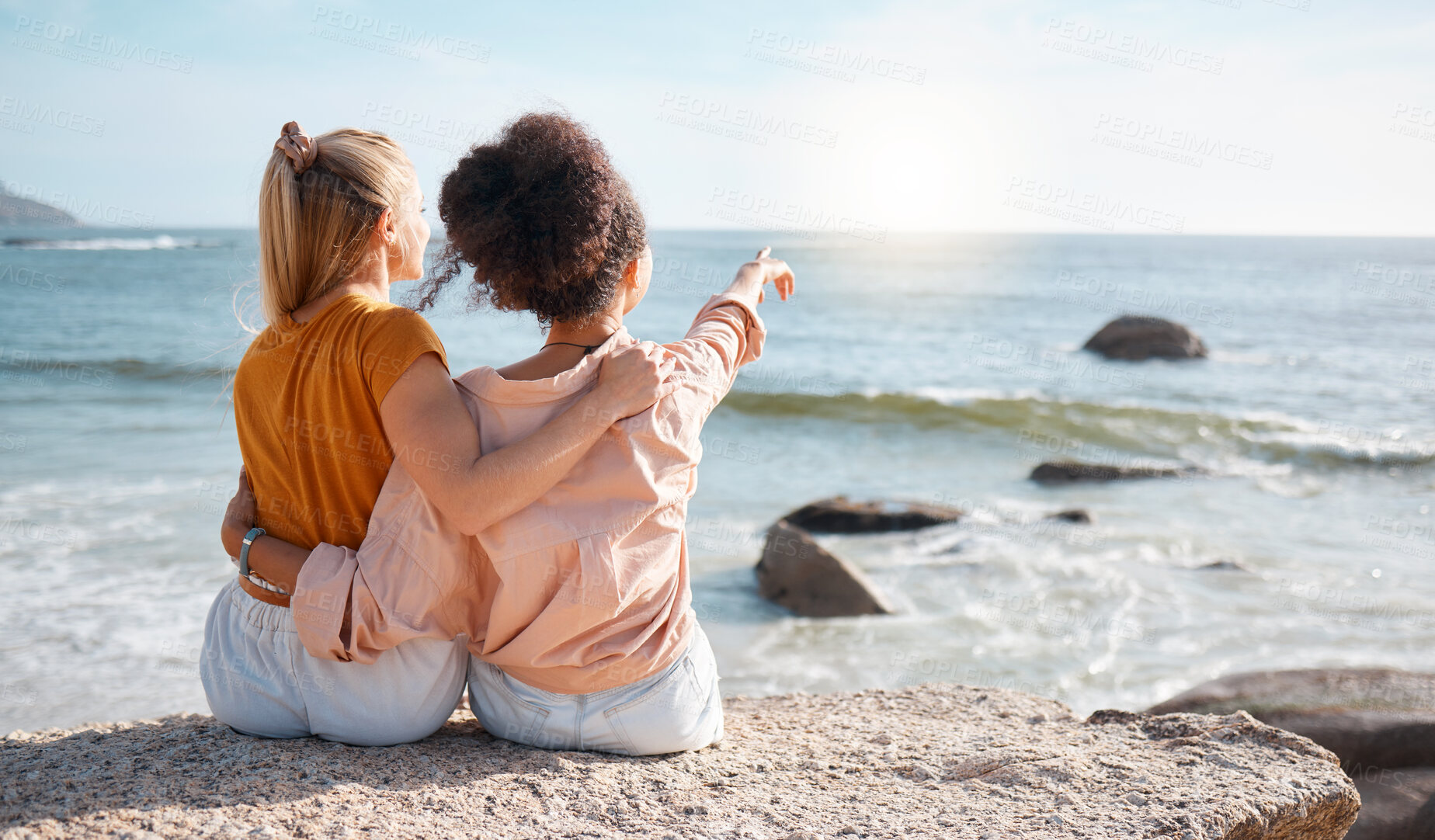 Buy stock photo Beach, rear view and women pointing at the sea for travel, sightseeing or fun on vacation against blue sky background. Back, friends and ladies relax at ocean with peace, freedom and bond in Miami