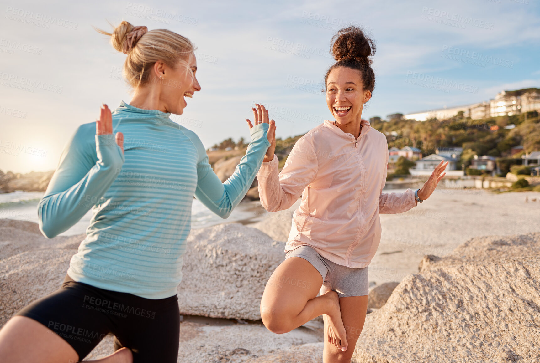 Buy stock photo Women friends, yoga and ocean in morning with stretching pose for health, zen wellness or high five for support. Black woman, exercise group and comic laugh for balance, peace and solidarity at beach