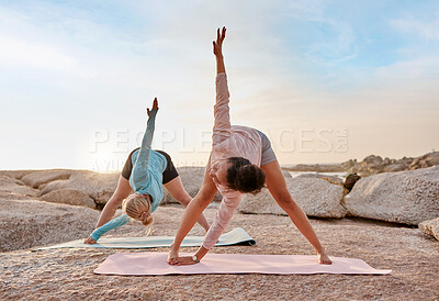 Buy stock photo Friends, yoga or stretching on beach mat for relax training, workout or exercise for healthcare wellness, muscle relief or flexibility. Women, yogi or pilates people on rock for zen fitness at sunset