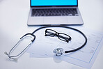 Laptop, stethoscope and medical documents in a office for research, diagnosis or test results. Computer, technology and glasses on a desk for doctor to read healthcare paperwork in hospital or clinic