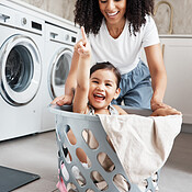 Mom, laundry and girl kid in basket by washing machine for cleaning ...