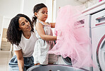 Mom, girl child and teaching at washing machine with fabric, cloth or clothes in house with helping hand. Black woman, mother and daughter with laundry, learning or help for life skill in family home