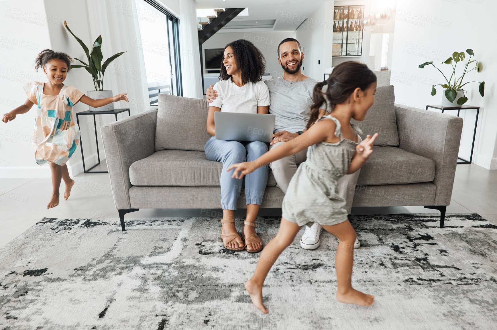 Buy stock photo Black family home, kids and running in living room for game, bonding or funny time with parents on sofa. Children, mother and father on lounge couch with laptop, smile and happiness for love together