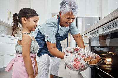 Buy stock photo Muffins, learning and grandmother with girl cooking and taking out cupcakes from oven. Education, kitchen and happy grandma teaching child how to bake, bonding and enjoying quality time together.