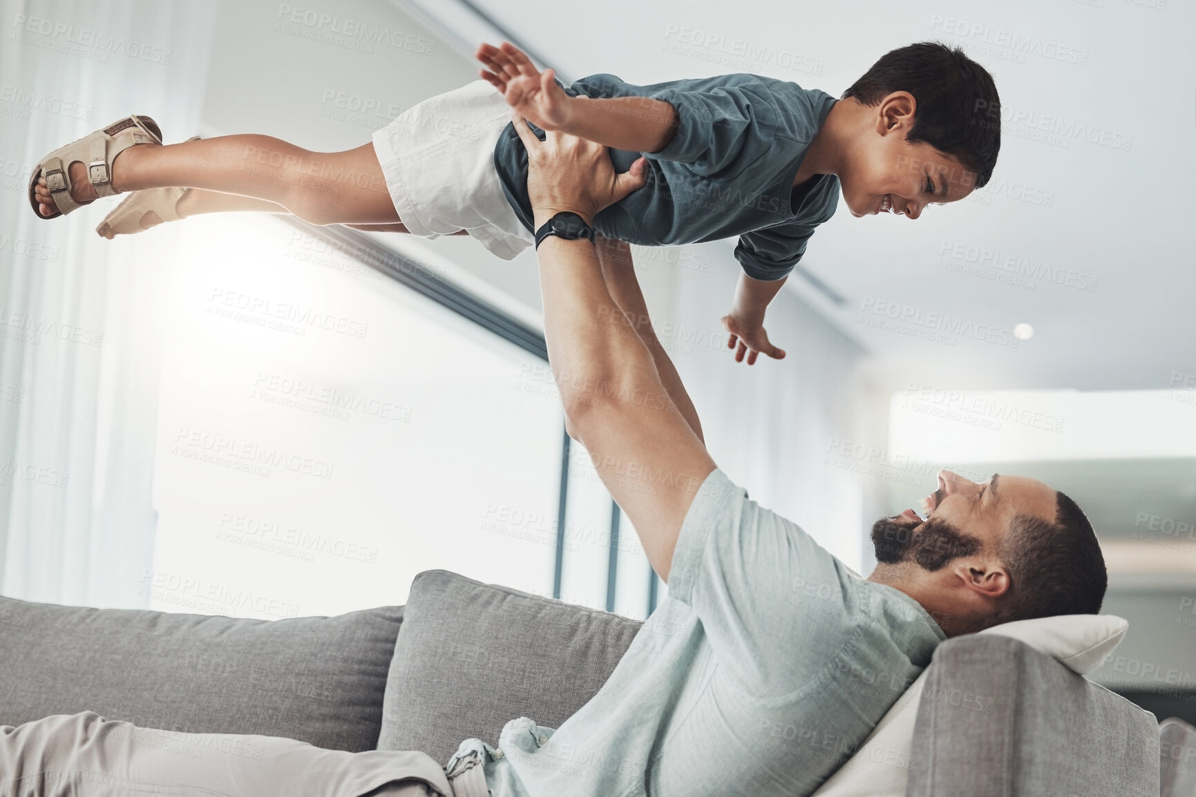 Buy stock photo Relax, smile and lifting with father and son on sofa of living room for bonding, playful and support. Wellness, game and strong with dad and child in family home for care, quality time and happy