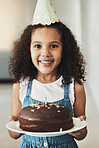 Happy girl with birthday cake, portrait with child in home and surprise celebration in Atlanta house alone. Young kid with smile in homemade chocolate dessert, hat on curly hair and excited wow