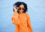 Trendy, portrait and woman with sunglasses by a wall in the city on a vacation or weekend trip. Happy, smile and female with orange, fashion or stylish eyewear in town while on a holiday in Mexico.