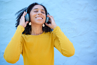 Buy stock photo Headphones, black woman and happy music on wall background, blue backdrop and mockup. Excited girl listening to radio, podcast and sound of streaming, audio and face of smile, relax and hearing tech