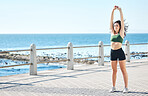 Fitness, body stretching and exercise by woman at beach for run, sport and cardio on blue sky background. Mindset, stretch and workout by girl at ocean for training, calm or relax, warm up or routine
