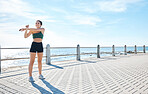 Fitness, woman and stretching arms at the beach for running, exercise or cardio workout outdoors. Active female runner in warm up arm stretch preparation for run, exercising or training in nature