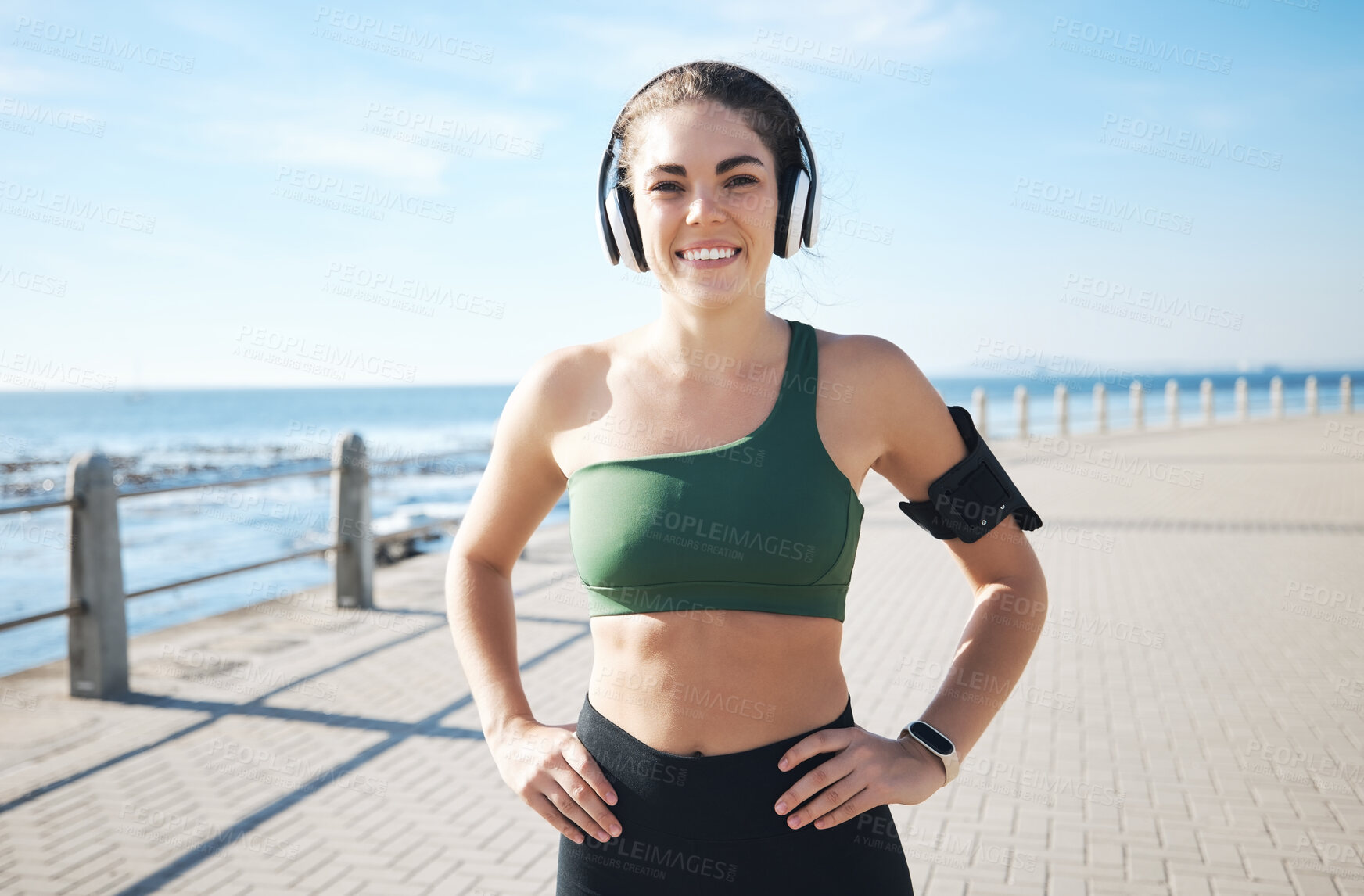 Buy stock photo Music, fitness and portrait of woman at beach for running, exercise and cardio on blue sky background. Radio, podcast and workout run by girl at ocean in training, happy or relax for audio motivation