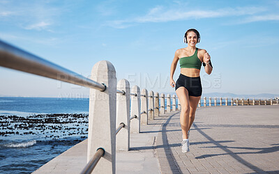 Buy stock photo Running, music and woman at beach for fitness, exercise and morning cardio with energy in sports. Radio, podcast and workout run by girl at ocean for training, happy or relax with audio motivation
