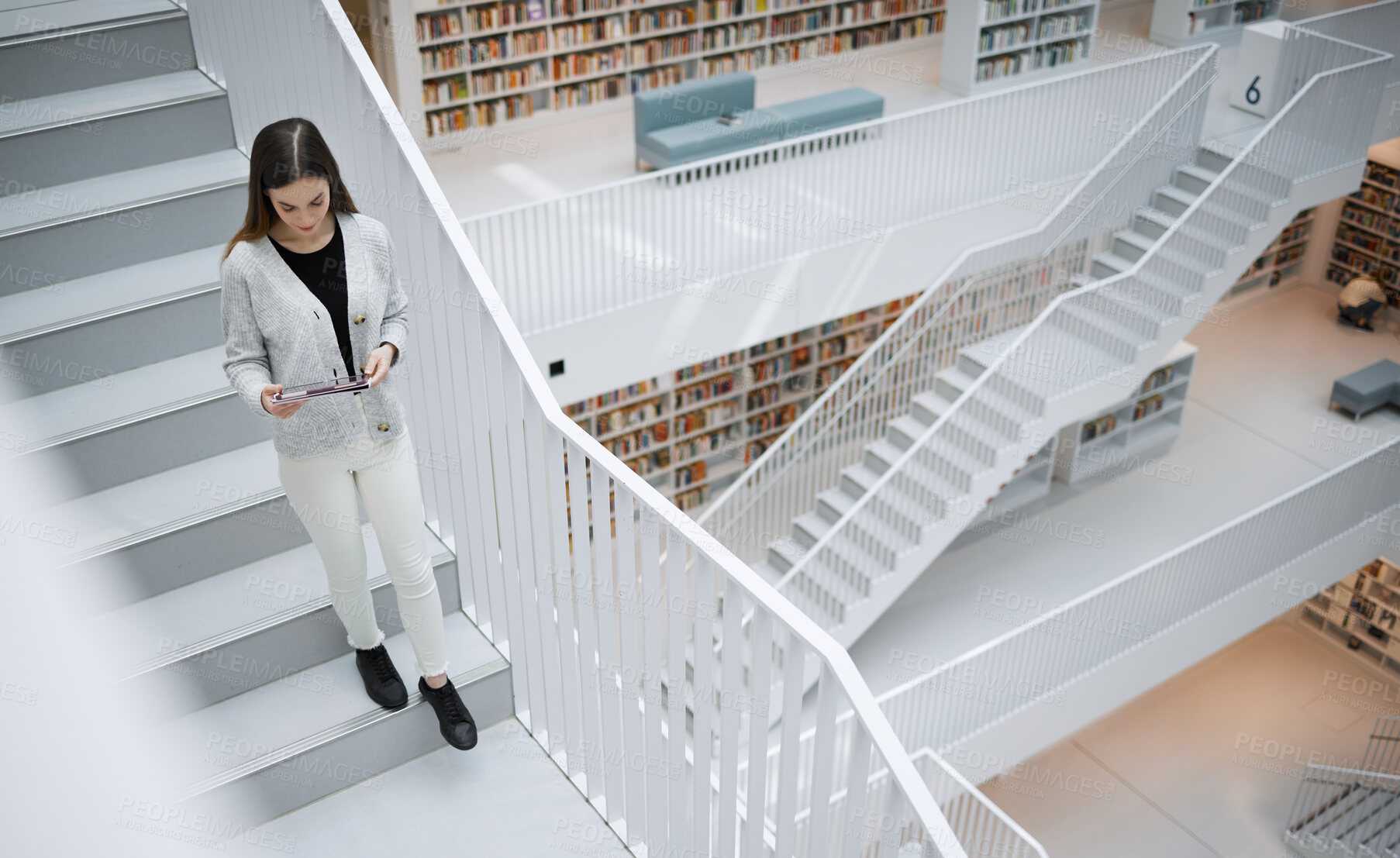 Buy stock photo Top view, stairs and woman in library, tablet or online research for university, reading or education. Female, girl or student with device, bookshelves or search internet for knowledge or information