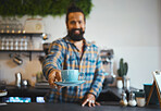 Cafe, serving and man barista with a coffee for a customer in his small business restaurant. Happy, smile and male waiter or server giving a cup of cappucino, latte or espresso in his cafeteria shop