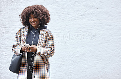 Buy stock photo Black woman, phone and portrait smile listening to music with earphones in fashion and afro hairstyle on mockup. Happy African American female holding smartphone for audio track on a wall background