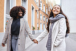Woman, friends and holding hands with smile for travel, friendship or fun journey together in the city.  Happy women walking touching hand and smiling for funny outdoor traveling in an urban town