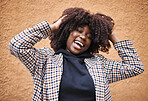 Black woman, laughing and afro for fashion, style or hair against a wall background. Portrait of happy African American female model touching stylish curls and smiling in happiness for haircare