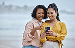 Phone, beach and social media with black woman friends outdoor together by the ocean or sea in the morning. Nature, mobile or internet with a young female and friend reading a text on the coast
