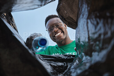 Buy stock photo Recycle, smile and black man with view in bag, sustainability and cleaning plastic pollution, earth day and help in community. Saving the environment, charity and people putting trash in garbage bin.