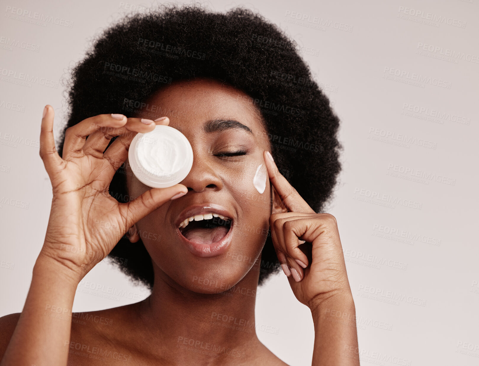 Buy stock photo Skincare, beauty and black woman holding cream on face, afro and excited advertising luxury skin product promotion. Dermatology, spa cosmetics and facial for happy model isolated on studio background