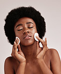 Black woman, skin care and cotton for cleaning face in studio with dermatology, cosmetic and detox. Aesthetic model with hands on natural facial skin for makeup removal, beauty and wellness for spa