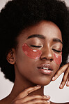 Black woman with skincare, eye or face mask in studio with dermatology cosmetic product. Aesthetic model with hand on skin for spa collagen beauty patch for health, wellness and natural facial glow