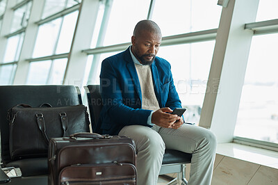 Buy stock photo Black man, phone and luggage at airport for business travel, trip or communication waiting for flight. African American male traveler chatting or checking plain times, schedule or delay on smartphone