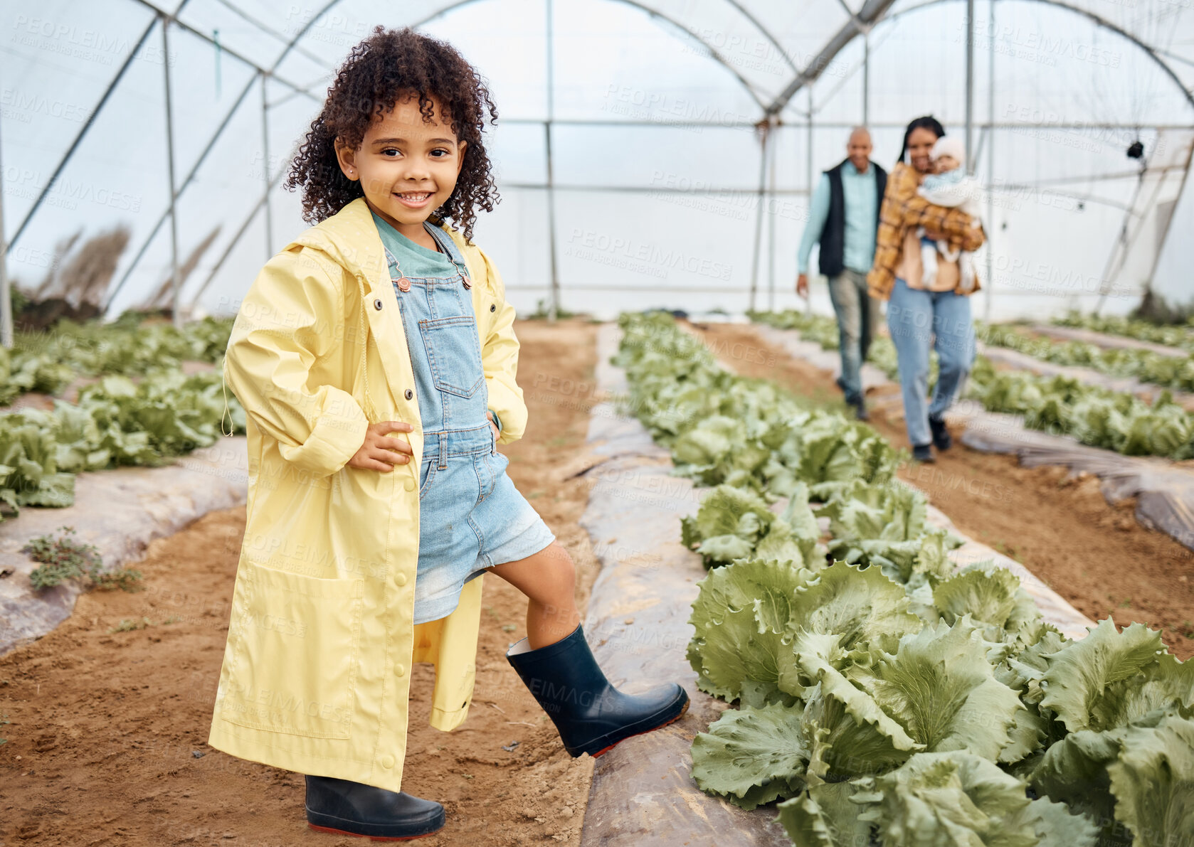 Buy stock photo Kid, happy or girl in farming portrait, akimbo or hands on hips in greenhouse, agriculture land or sustainability field pride. Smile, child or learning gardening in countryside nature or lettuce agro