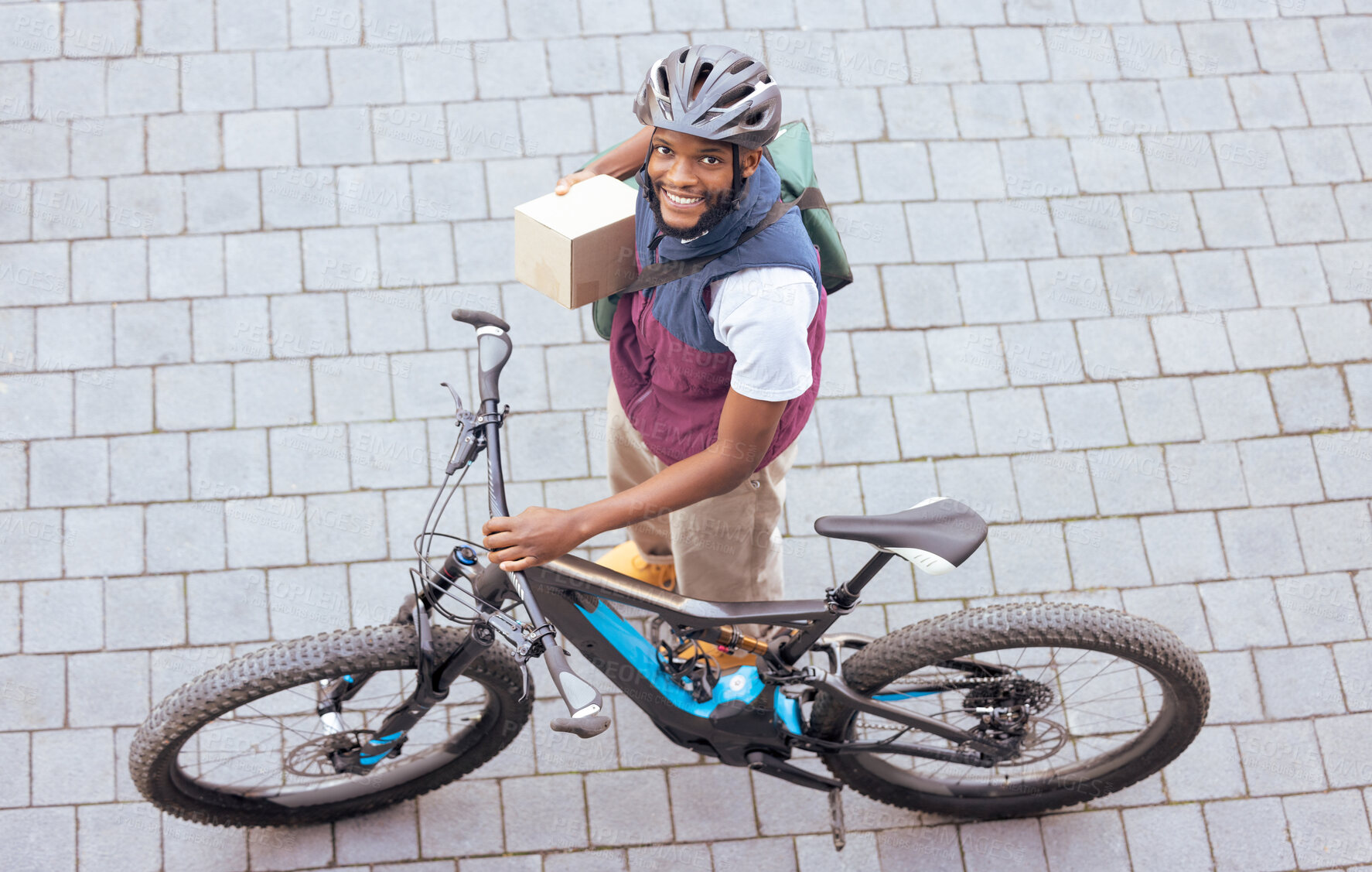 Buy stock photo Black man, delivery bike and street portrait from top view for logistics, cargo and happy for job. Young african person, bicycle and shipping service with box package, helmet and safety in metro