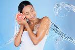 Beauty model, water splash or skincare grapefruit on blue background in facial hydration, healthcare or isolated wellness. Black woman, happy or wet with citrus food for vitamin c or face dermatology