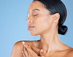 Beauty, water splash or washing face in shower grooming, healthcare or sustainability cleaning on isolated blue background. Zoom, black woman or model in wet drops for skincare hydration dermatology