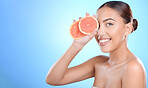 Skincare, portrait and woman with grapefruit in studio for cosmetics, wellness and treatment on blue background. Face, beauty and girl model on fruit, product and luxury cleaning, grooming or hygiene