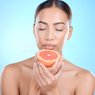 Buy stock photo Skincare, woman and grapefruit scent for in studio for beauty, smell and cosmetics on blue background. Fruit, citrus and product for girl skin model relax in luxury, pamper or routine while isolated