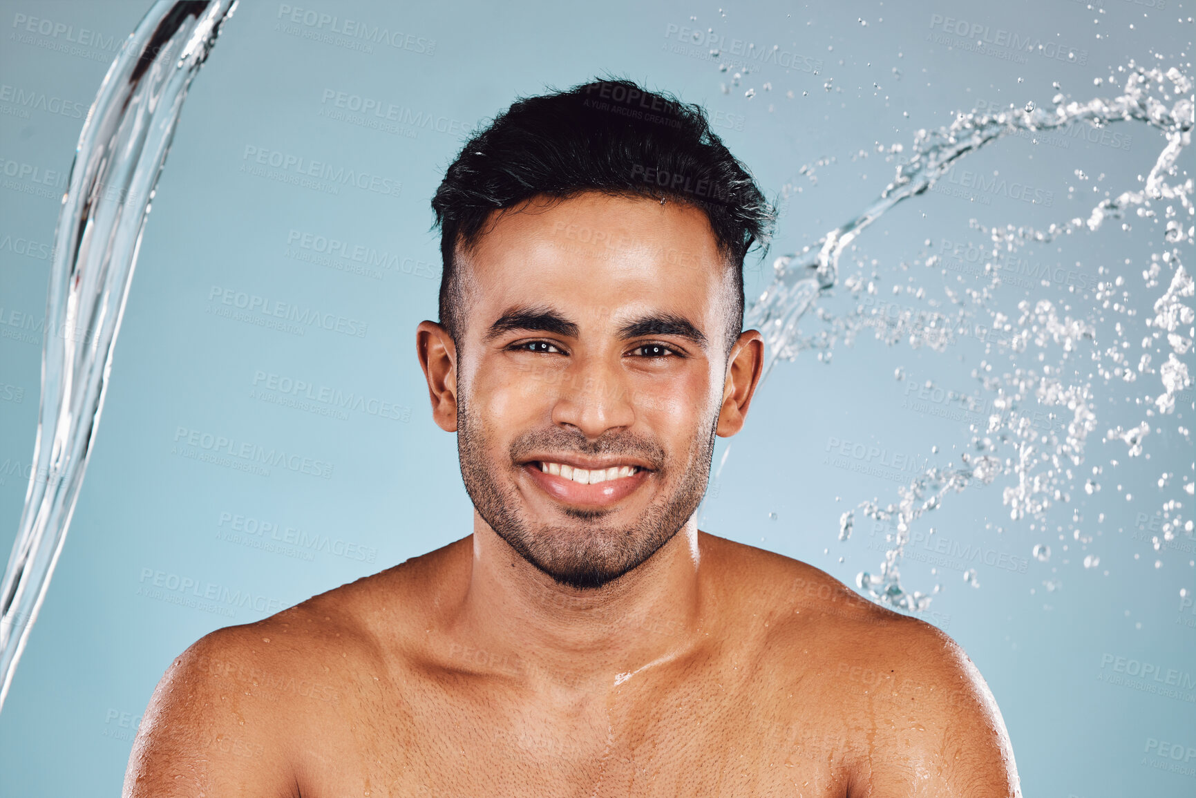 Buy stock photo Water splash, portrait and beauty man isolated on blue background face cleaning, body shower and smile. Happy, skincare model or person facial glow in studio headshot washing and dermatology hygiene