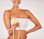 Healthy, tape measure and body with black woman and apple for nutrition and diet with fitness isolated on studio background. Wellness, smile and health lifestyle with weightloss and clean eating 