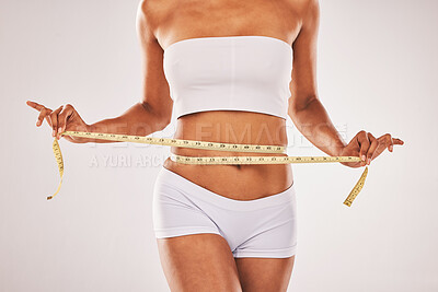 Buy stock photo Weight, loose and woman with tape for stomach isolated on a grey studio background. Diet, health and girl measuring her waist for slim shape, motivation and belly while standing on a backdrop
