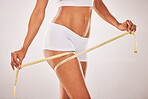 Woman, body and lose weight with tape measure on thigh for healthy diet, health and wellness. Model studio background for fitness, goals and motivation in underwear for exercise results and progress