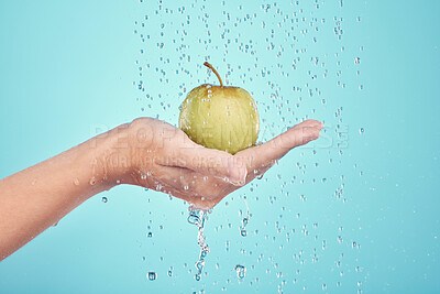 Buy stock photo Water splash, cleaning and hands with apple in studio isolated on a blue background. Nutritionist, fruits and model or woman washing food for healthy diet, vitamin c or skincare, beauty or wellness.