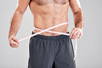 Fitness, weightloss and man with measuring tape on waist, healthy diet and exercise in body care. Sports, nutrition and stomach, tracking weight loss and six pack progress isolated on grey background